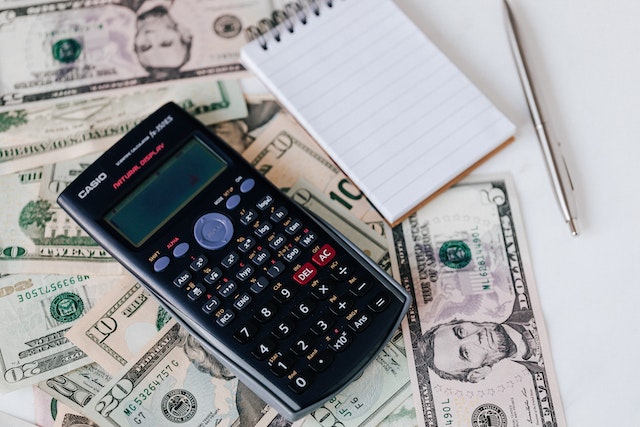 calculator atop sperad out bills of money